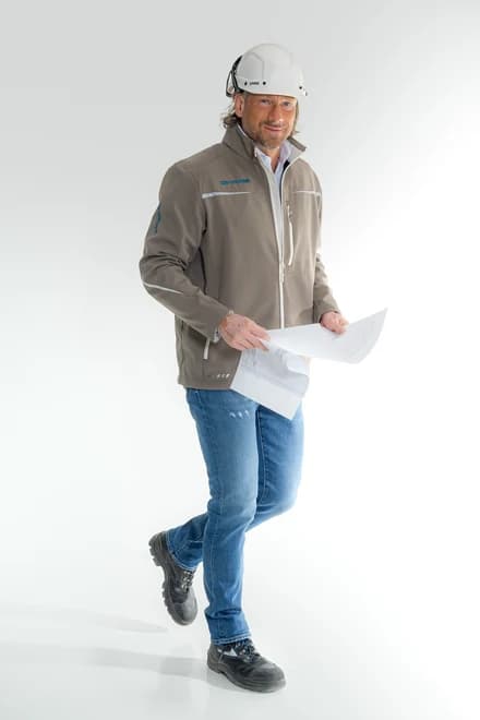 Christian Becker-Sonnenschein von cbs-concept in Arbeitsjacke und Schutzhelm, mit Bauplänen in der Hand